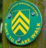 Bury to Clare Walk waymarker disc on wooden post Bury to Clare Walk green and yellow waymarker disc on wooden post