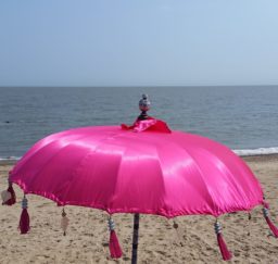 a large bright pink parasol on the sandy beach at Felixstowe