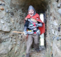 child having fun dressed as a knight exploring a flint tunnel at Framlingham Castle
