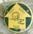 green and yellow Fynn Valley Path waymarker disc attached to a wooden fence