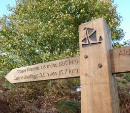 a wooden Sailors' Path finger post with the black barge logo and pointing to Snape Warren 1.6 miles and Snape Maltings 3.5 miles, on a sunny day