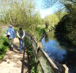 Two people enjoying a stroll along the path next to the River Lark on a sunny day