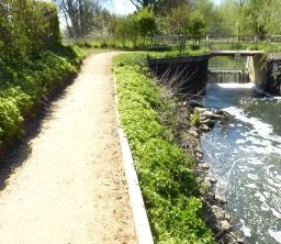 footpath leading to a footbridge over the weir on the River Lark on a sunny day