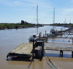 a view of boats moored at jetties along the River Blyth at Southwold Harbour on a sunny day