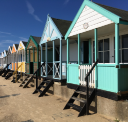 Colourful beach huts along the prom at Southwold on a sunny day