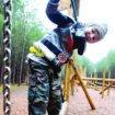 child on climbing equipment at Rendlesham Forest, with tall trees in the background